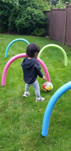 a toddler playing with an inflatable ball on the grass next to some blue and pink circles