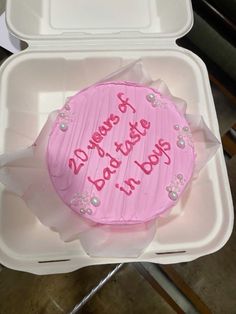 a pink frosted birthday cake in a plastic container with writing on the side and inside