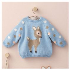 a blue sweater with a deer on it is hanging next to a pair of scissors