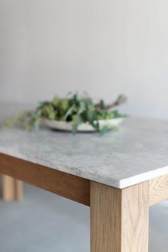 a bowl of green leaves sitting on top of a table