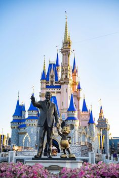 a statue of walt and mickey mouse in front of a castle