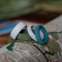 two wedding rings are sitting on top of a map with blue and white bands around them