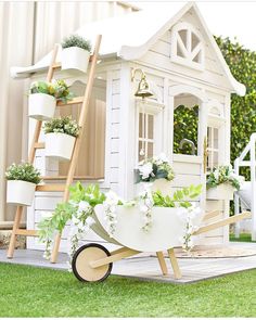 a doll house with flowers and plants in the wheelbarrow, on display outside