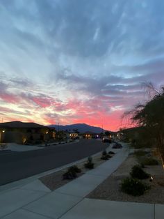 the sky is pink and blue as the sun goes down in the distance with mountains in the background