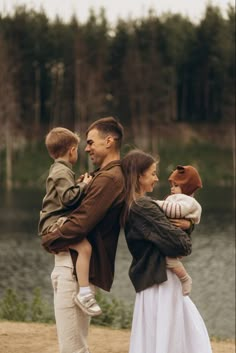 a man holding a baby while standing next to two women and a child on the beach