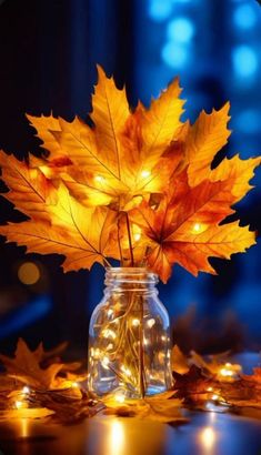 a glass jar with some lights in it and a leaf on the table next to it