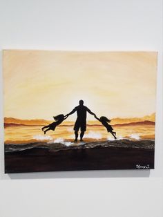 a man and two children holding hands while standing in the ocean at sunset with their arms around each other