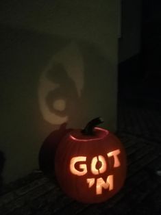 a carved pumpkin with the word got'm carved into it, sitting in front of a wall