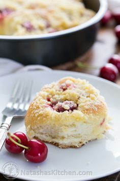 a piece of cake on a plate with cherries next to it and a fork