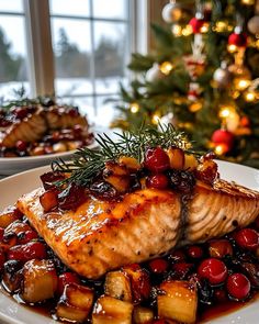 a white plate topped with meat covered in cranberry sauce next to a christmas tree