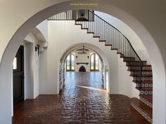 an arched entry way leading to a foyer with red brick flooring and white walls