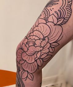 a woman's leg with flowers on it and an ornate tattoo design in the middle