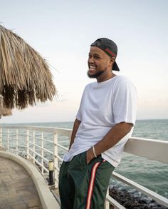 a man standing on the side of a pier next to the ocean with his hands in his pockets