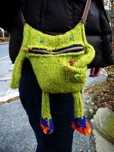 a woman is holding a green purse with an animal on it's back pocket