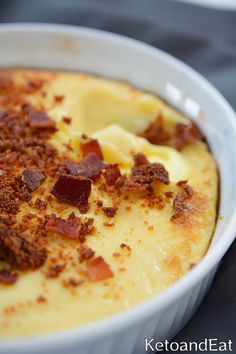 a bowl filled with cheese and bacon on top of a table next to a fork