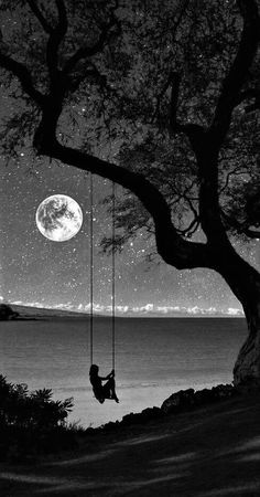 a black and white photo of a person swinging from a tree with the moon in the background