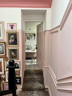 the hallway is decorated in pink and white with pictures on the wall, framed by an ornate doorway