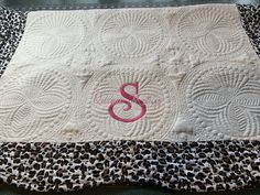 a close up of a quilt with the letter s on it and a leopard print blanket