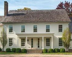 a large white house with lots of windows on the front and side of it's roof