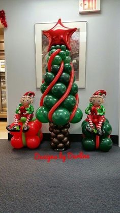 an inflatable christmas tree with two elfs sitting on the top and one standing next to it