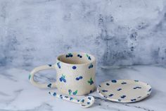 a ceramic cup and saucer sitting on a marble counter top next to a spoon