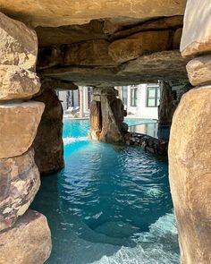 an indoor swimming pool with large rocks surrounding it and water running through the hole in the middle