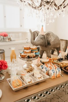 an elephant statue is standing next to a table full of desserts and pastries