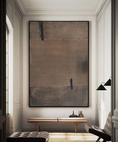 a painting hanging on the wall above a bench in a room with white walls and wooden flooring