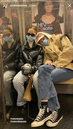 two people sitting on a subway with masks covering their faces and one person wearing a face mask