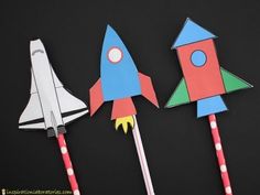 three paper rockets sitting next to each other on top of a black surface with red, white and blue sticks sticking out of them