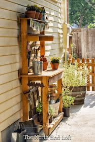 a wooden shelf filled with potted plants next to a house