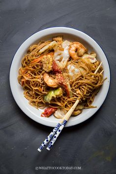 a white plate topped with noodles and shrimp