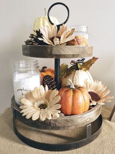 a three tiered tray with candles and pumpkins on it, sitting on top of a table