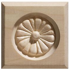 a carved wooden object with a circular design on the front and center piece in white wood