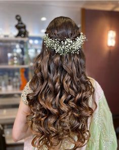 the back of a woman's head with long hair and flowers in her hair