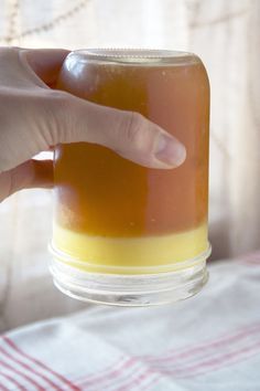 a person is holding a jar with liquid in it and pointing to the top one