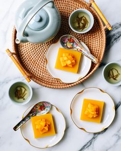 three pieces of cheese sitting on plates next to cups and saucers with spoons