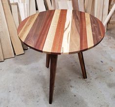 a wooden table sitting on top of a floor next to stacks of wood planks