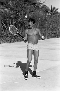 a shirtless man holding a tennis racquet and ball