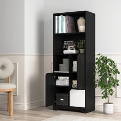 a black bookcase with books and magazines on it next to a chair in a white room