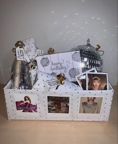 a white box filled with pictures and other items on top of a wooden table next to a silver disco ball