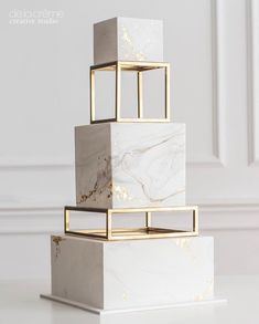 a white and gold marble cake sitting on top of a table next to a wall