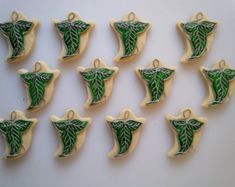 twelve decorated cookies arranged in the shape of an ornament with green leaves on them