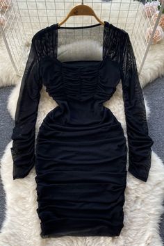 a black dress on a hanger in front of a white rug