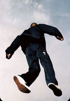 a man flying through the air while riding a skateboard in front of a blue cloudy sky