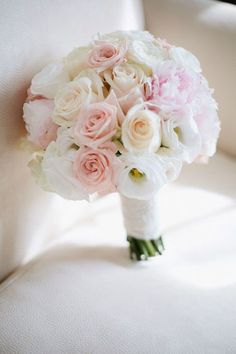 a bridal bouquet sitting on top of a white chair with pink and white flowers