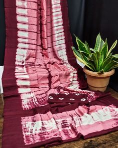 a potted plant sitting on top of a wooden table next to a red and white blanket