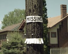 a telephone pole that has some stickers on it and is covered in paper with the word missing