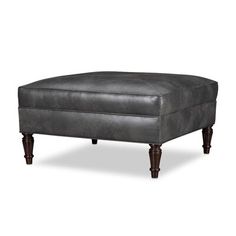 an ottoman with wooden legs and grey leather upholstered