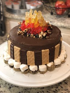 a chocolate cake topped with gummy bears and marshmallows on a white plate